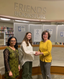 2023 Friends of the Library Scholarship winner Sidney Adams stands with Friends President Vanessa Hale and Library Director Priya Rathnam in front of the Friends Bookstore on the lower level.